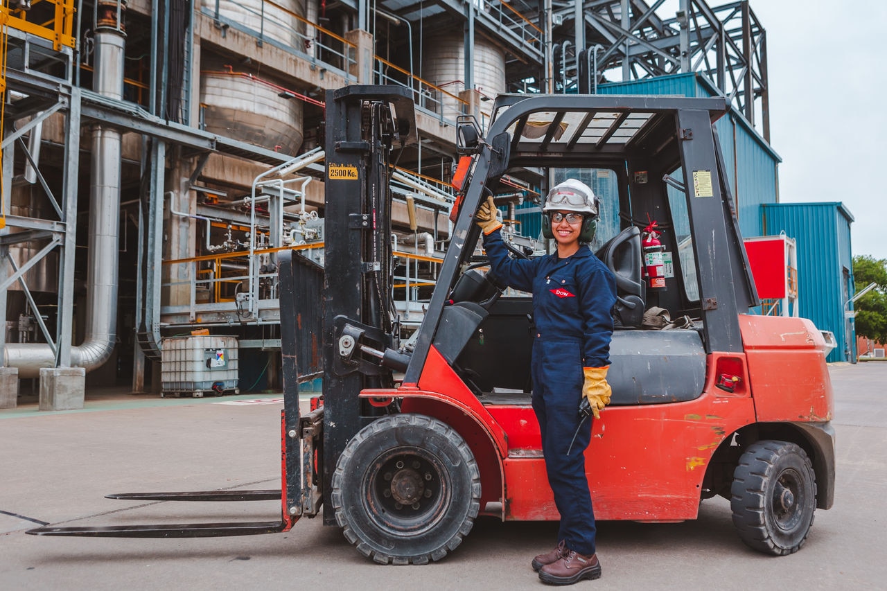 Young female employee posing for a picture in front of a forklift at BahÃ­a Blanca facility.