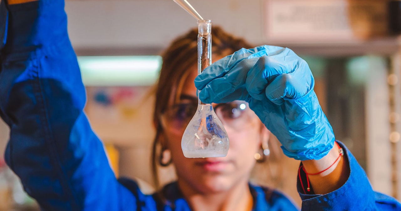 female scientist adding material to flask